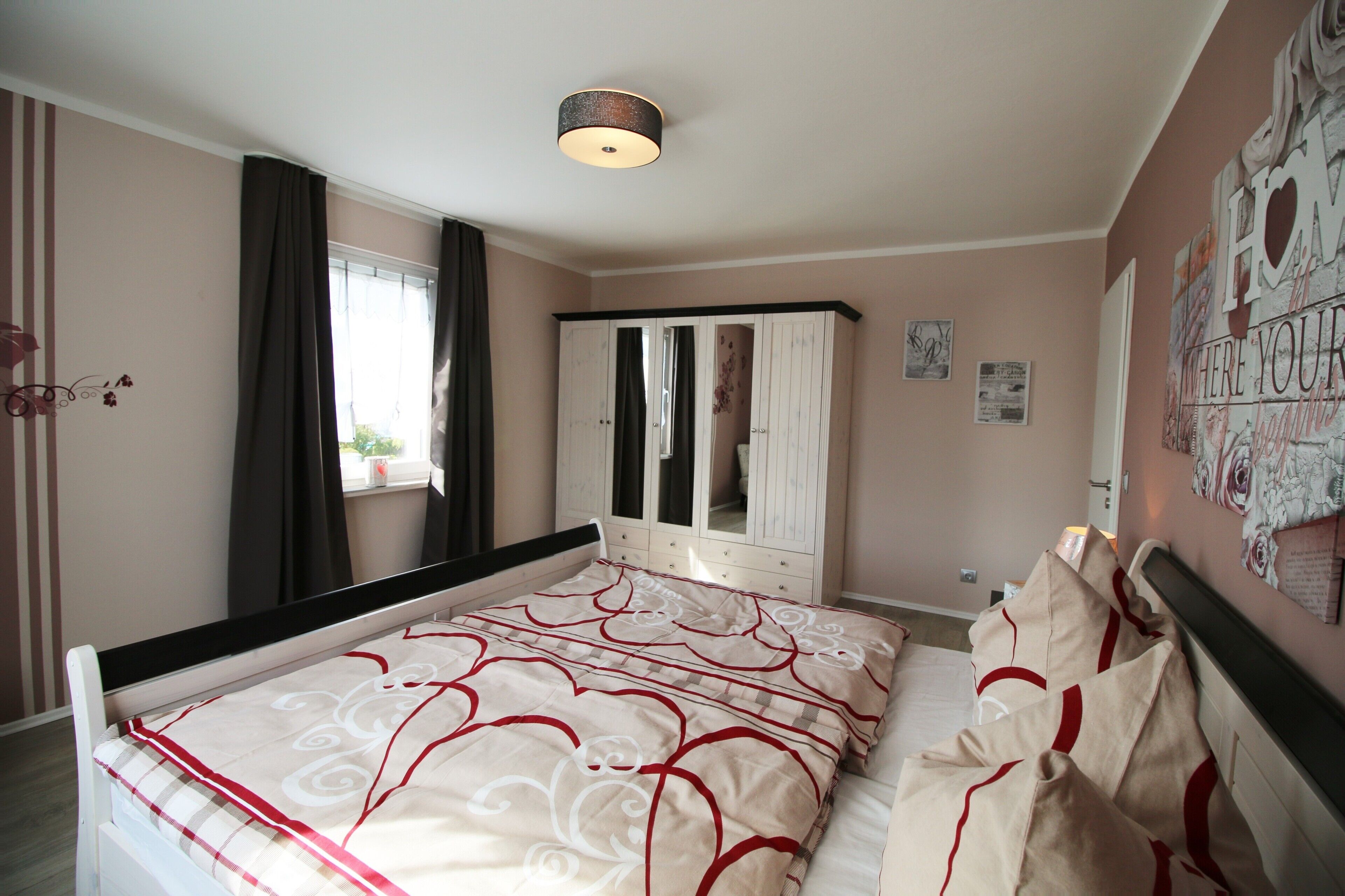 A bedroom with a bed, a wardrobe, a mirror, and a ceiling light.