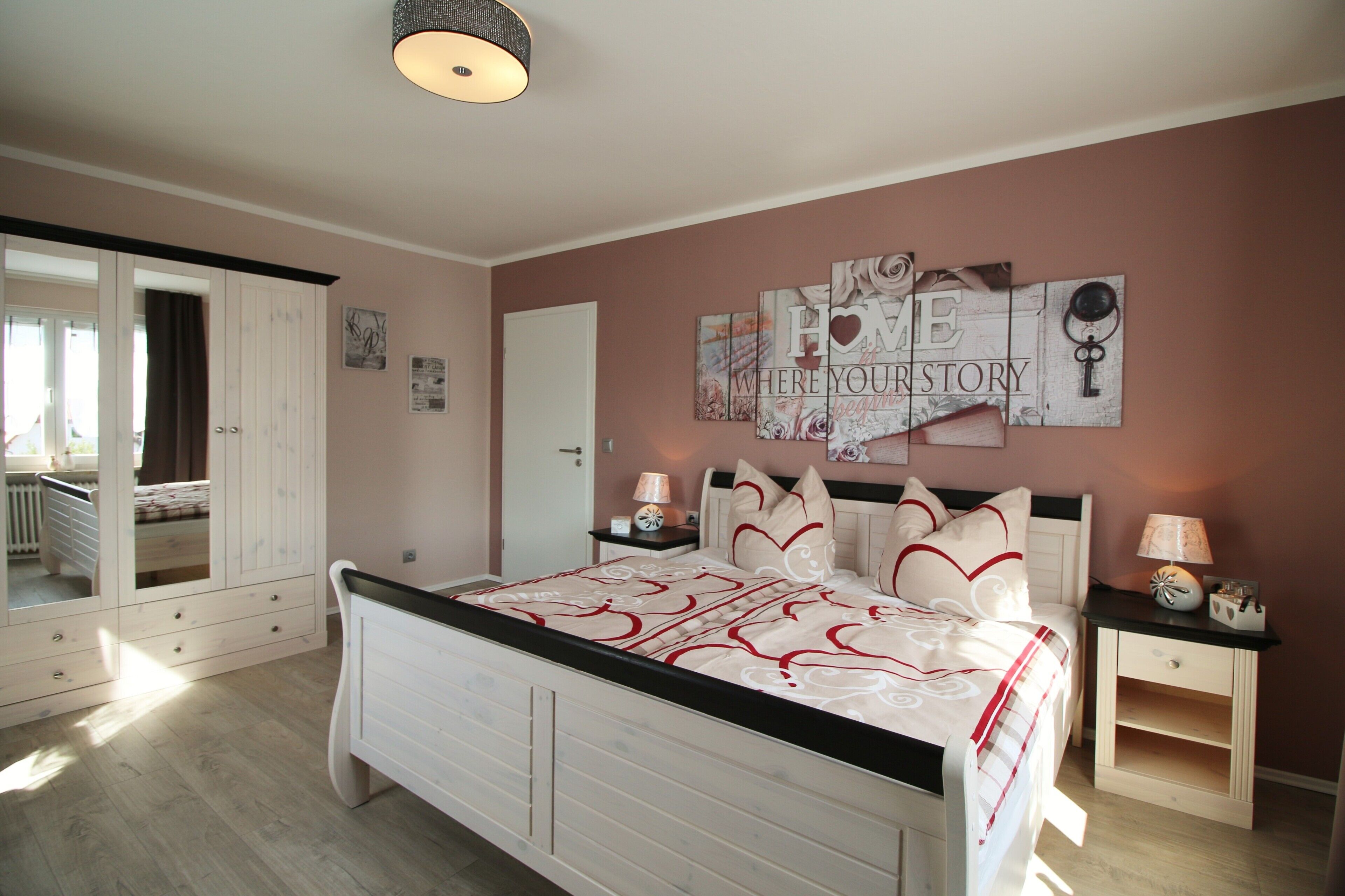 Un dormitorio con cama, mesitas de noche, un espejo y un adorno en la pared.