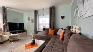 Una sala de estar con sofá, sillón, mesa de centro, televisor y elementos decorativos.