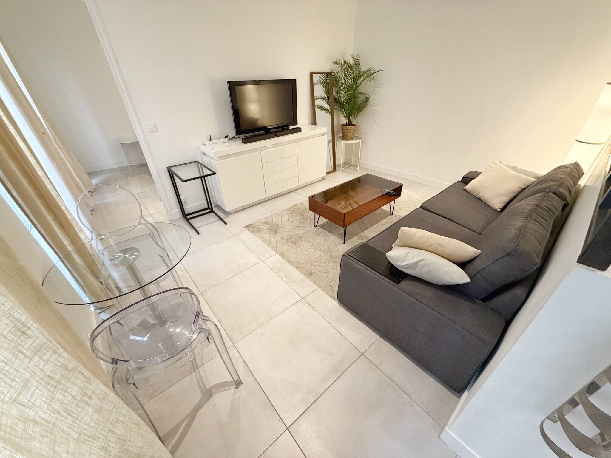 A modern living room with a sofa, coffee table, TV, and a small side table.
