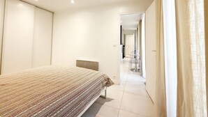 A bedroom with a bed, a chair, and a door leading to another room. - Charming studio in the heart of République (Paris)