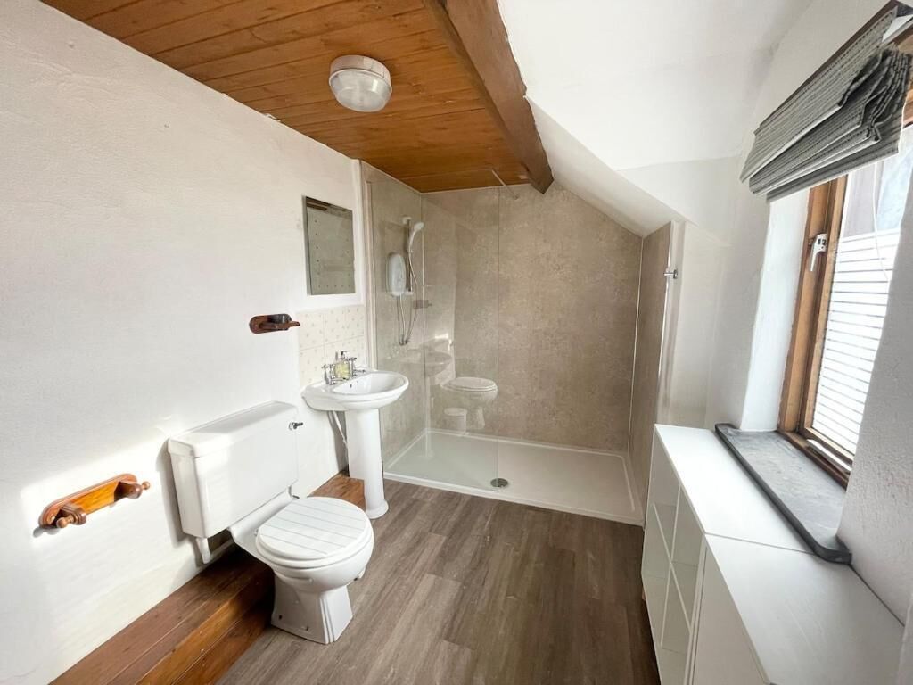 Uma casa de banho moderna com sanita, lavatório e chuveiro.