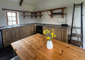 Een keuken met houten kastjes, een aanrecht, een spoelbak en een vaas met gele bloemen.