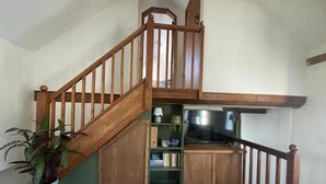 Una escalera de madera con un estante incorporado y una planta en maceta.