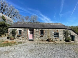 A stone cottage with a pink door, two windows, and a gravel driveway. - The Longhouse at Pencwm Escapes (Hebron)