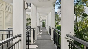 A corridor with white walls, black railings, and a concrete floor. - Sandy Toes Paradise at Paradiso 111 (Kingscliff)