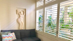 A living room with a sofa, colorful pillows, a glass coffee table, and a wall-mounted sculpture. - Sandy Toes Paradise at Paradiso 111 (Kingscliff)