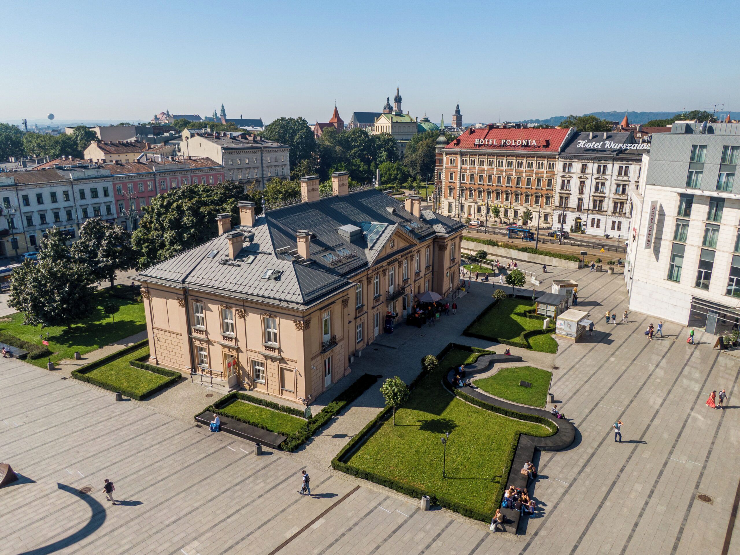 A large, historic building with a central courtyard, surrounded by other buildings, likely a hotel or public building.