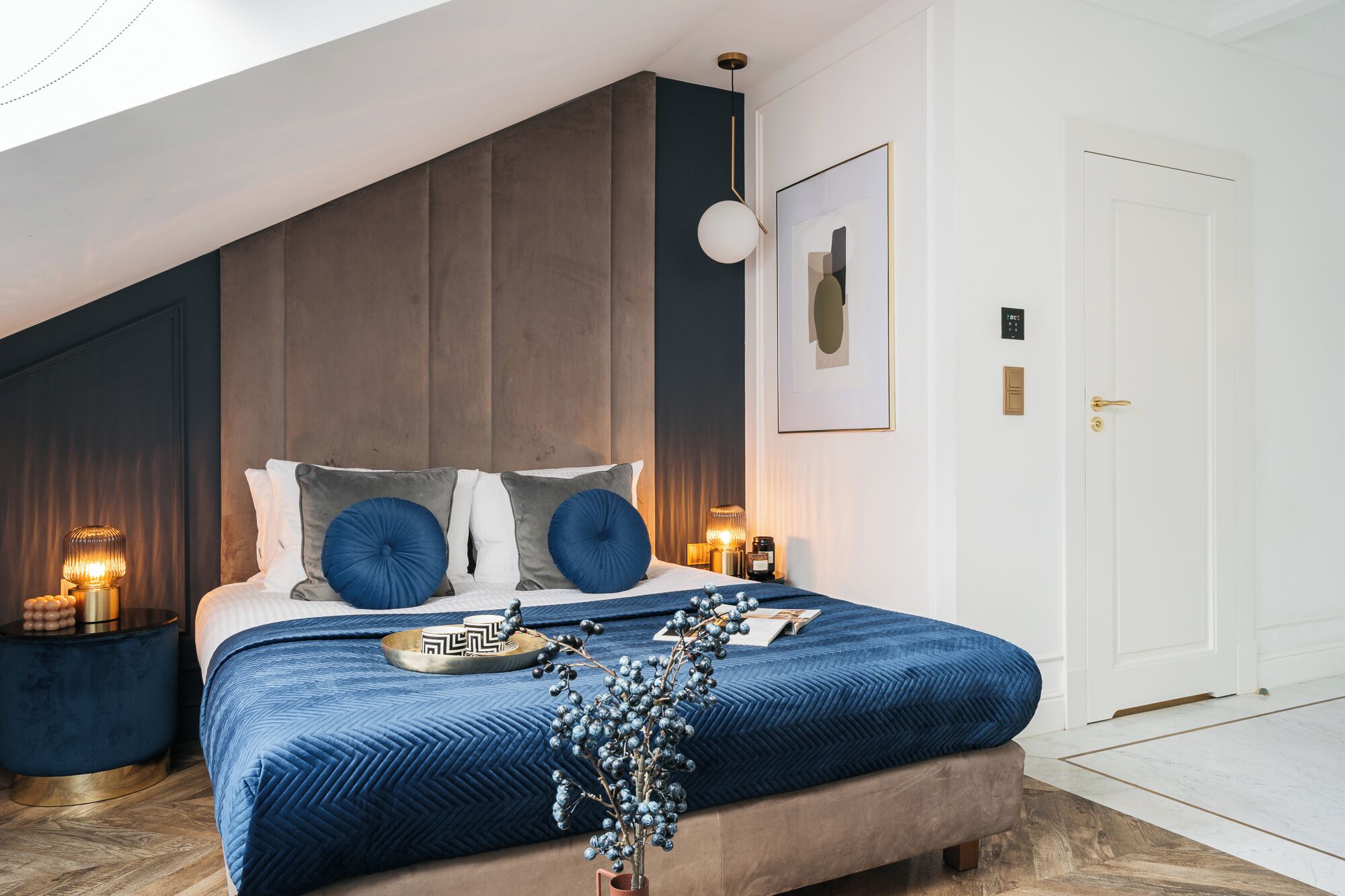 Un dormitorio con cama, mesitas de noche, una puerta y una lámpara en el techo.
