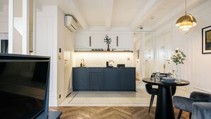 A modern kitchen with dark cabinets, a central island, and a dining area with a black table and chairs. - Central Palace (Kraków)