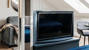 A modern living room with a flat-screen TV, a sofa, a chair, and a large mirror. - Central Palace (Kraków)