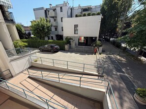 A multi-story residential building with a paved courtyard, a car parked in the driveway, and a pedestrian pathway. - Spacious apartment near Venice | Free private parking + direct streetcar Venice (Venezia)