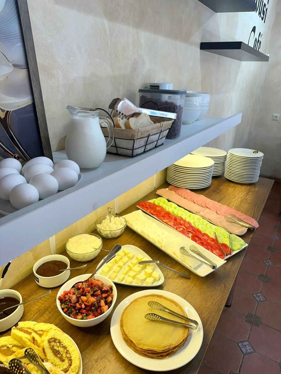 A breakfast buffet with various food items, including eggs, bread, and a variety of spreads.