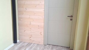 Ένας διάδρομος με ξύλινο τοίχο, μια πόρτα και ένα δάπεδο σε ανοιχτόχρωμο τόνο.