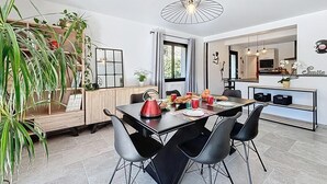 Un coin repas moderne avec une table noire, quatre chaises, une bouilloire rouge et une variété de plats.