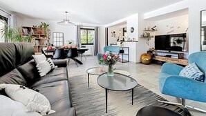 Un salon moderne avec un canapé, une table basse et un téléviseur. Il y a également un coin repas avec des chaises et une table.