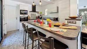 Une cuisine moderne dotée d’un îlot central, de luminaires suspendus et d’un four encastré.