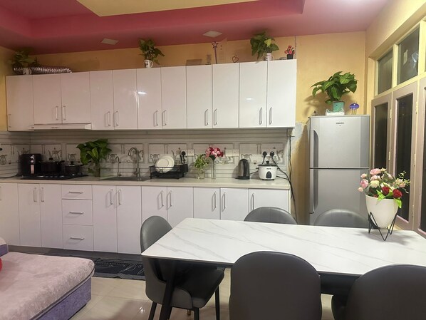 A modern kitchen with white cabinets, a marble countertop, and a dining area with a table and chairs.