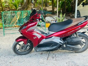 A red and silver motorcycle parked on a gravel surface.