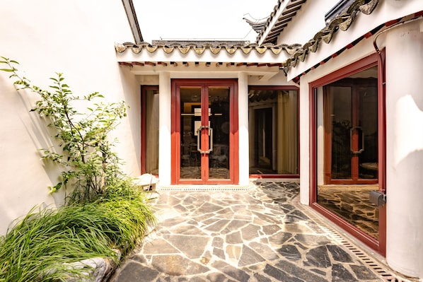 A traditional building with a tiled roof, a stone-paved entrance, and a red door. - Wu Palace Hotel Suzhou (Suzhou)