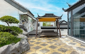 A traditional Chinese architectural courtyard with a tiled floor, a stone bench, and a hanging chair. - Wu Palace Hotel Suzhou (Suzhou)