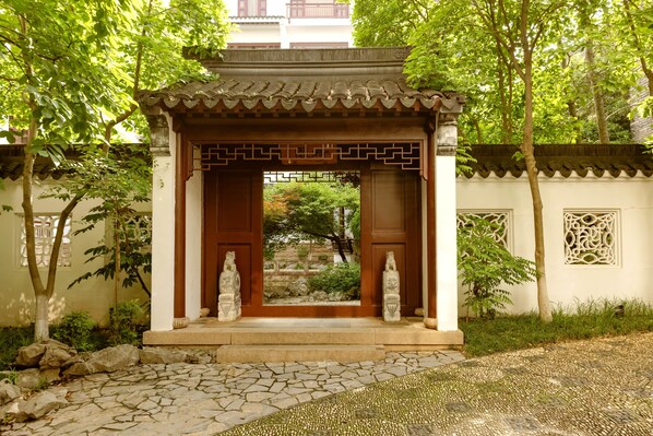 A traditional Japanese-style pavilion with a tiled roof, stone steps, and two stone statues. - Wu Palace Hotel Suzhou (Suzhou)