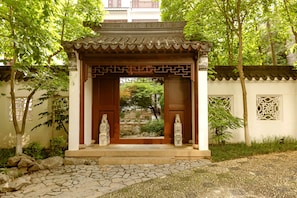 Perinteinen japanilaistyylinen paviljonki, jossa on laattakatto, kiviporras ja kaksi kivipatsasta.