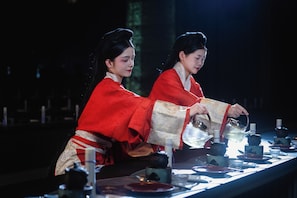 Two individuals in traditional attire serving tea at a table with various tea sets and cups. - Wu Palace Hotel Suzhou (Suzhou)