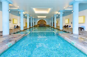 A large indoor swimming pool with clear water, surrounded by columns and benches, and a stone wall at the far end. - Wu Palace Hotel Suzhou (Suzhou)