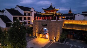 Um edifício tradicional com telhado em estilo pagode, entrada de pedra e uma placa com caracteres chineses.
