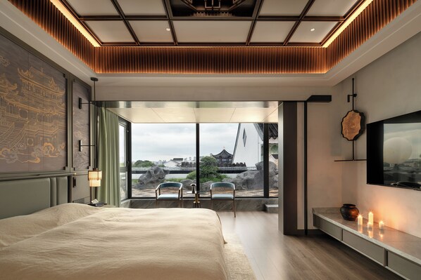 A modern bedroom with a large bed, a view of traditional architecture, and a television on the wall. - Wu Palace Hotel Suzhou (Suzhou)