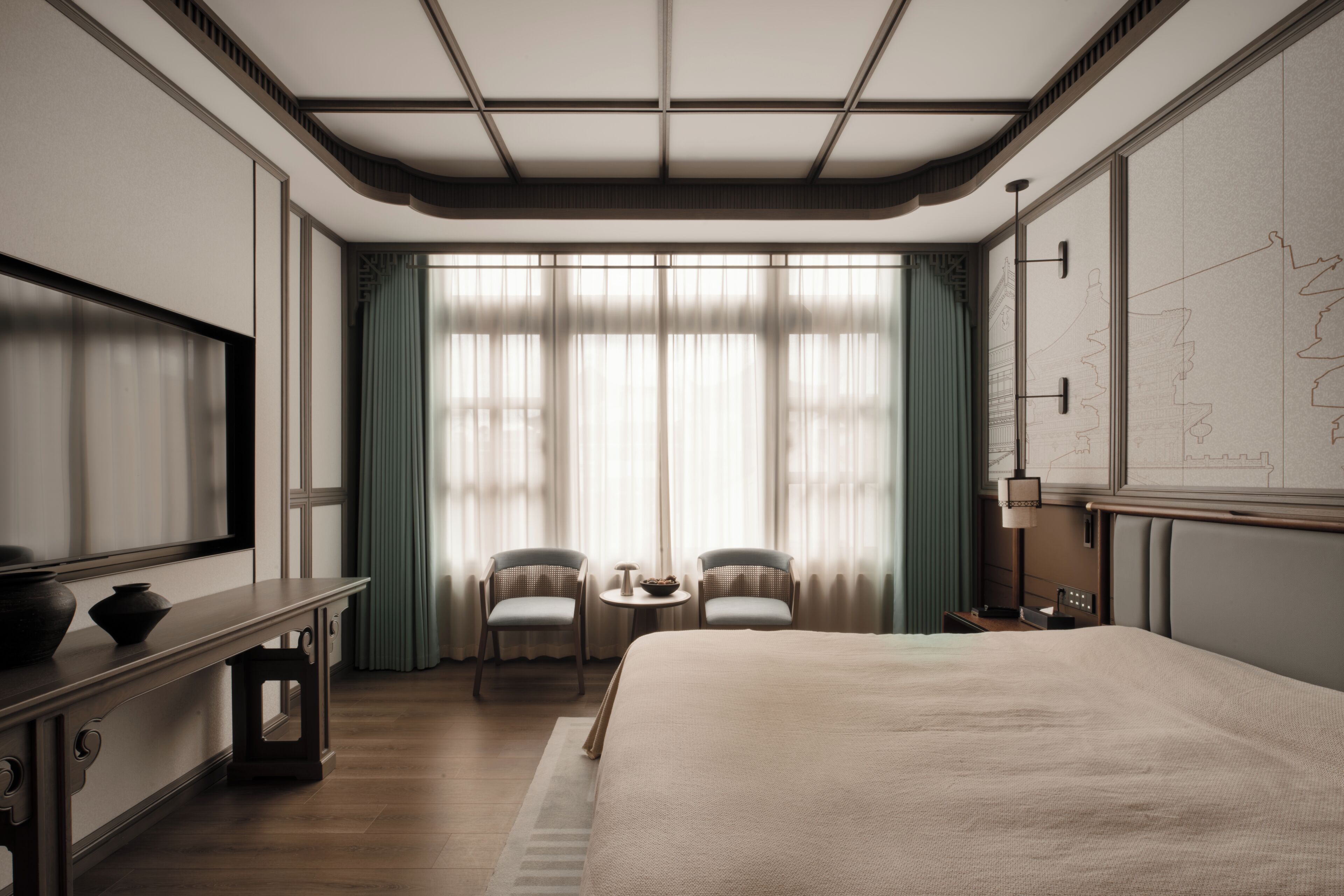 A hotel room with a large bed, two chairs, a small table, a TV, and a map on the wall.