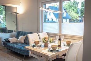 Un espace de repas moderne avec un canapé, une table à manger dressée avec des bols, des verres et un vase de fleurs.