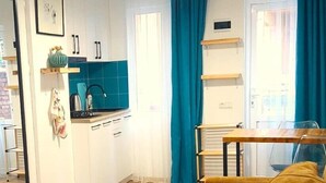 Un espace de vie compact comprenant un coin cuisine, un canapé et un coin repas.