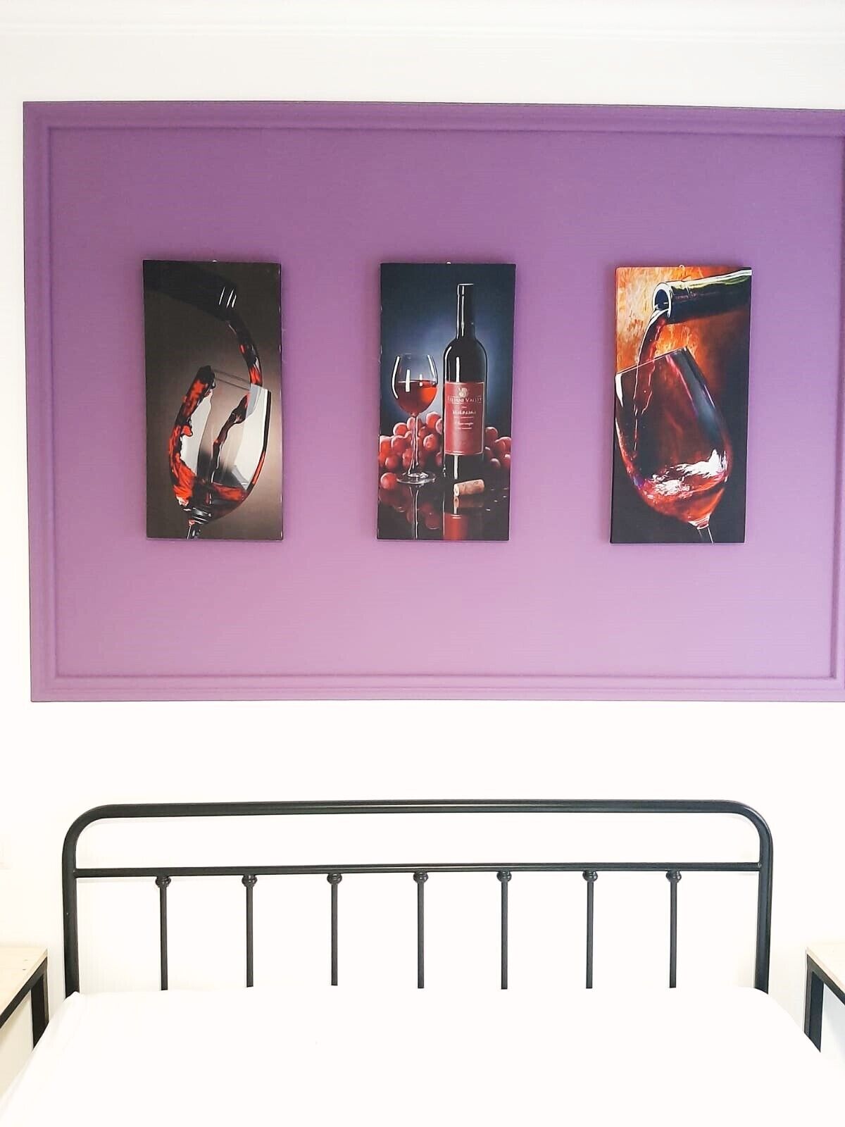 A wall with three framed pictures of wine glasses and bottles.