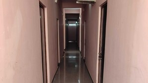A long, narrow hallway with a shiny floor and pink walls. - Kaku's Krishnabagh palace (Raipur Karchuliyan)