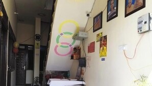 Una habitación con una cama, una mesita pequeña, una pared adornada con cuadros y un suelo de césped artificial verde.