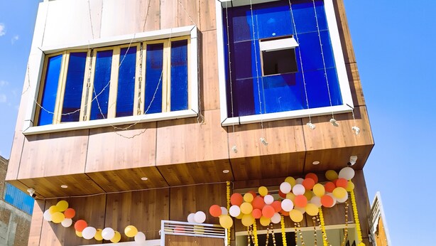 Un edificio de varios pisos con amplios ventanales, un balcón y una entrada protegida por una reja.