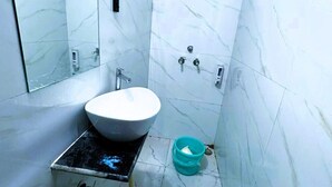 Un baño con lavamanos blanco, un espejo, inodoro y zona de ducha.