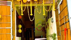 Entrada de un edificio con puerta de madera, un camino alfombrado de color verde y una pared decorada con globos y guirnaldas.