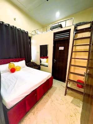Una habitación con cama, una escalera, una puerta y un ventanal.