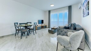 A modern living room with a dining area, a sofa, and a TV. - ARA Lux Apartments (Utjeha)