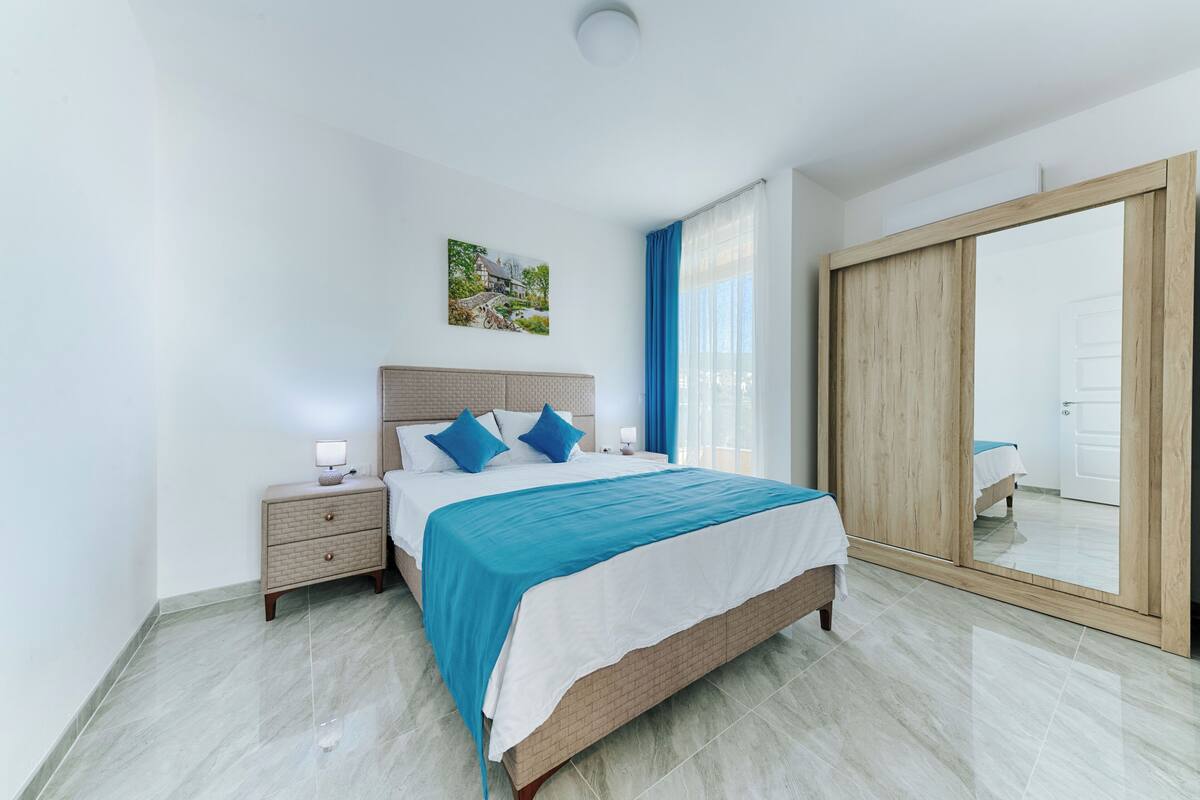 Une chambre moderne avec un lit, des tables de chevet, un grand miroir et une porte coulissante.