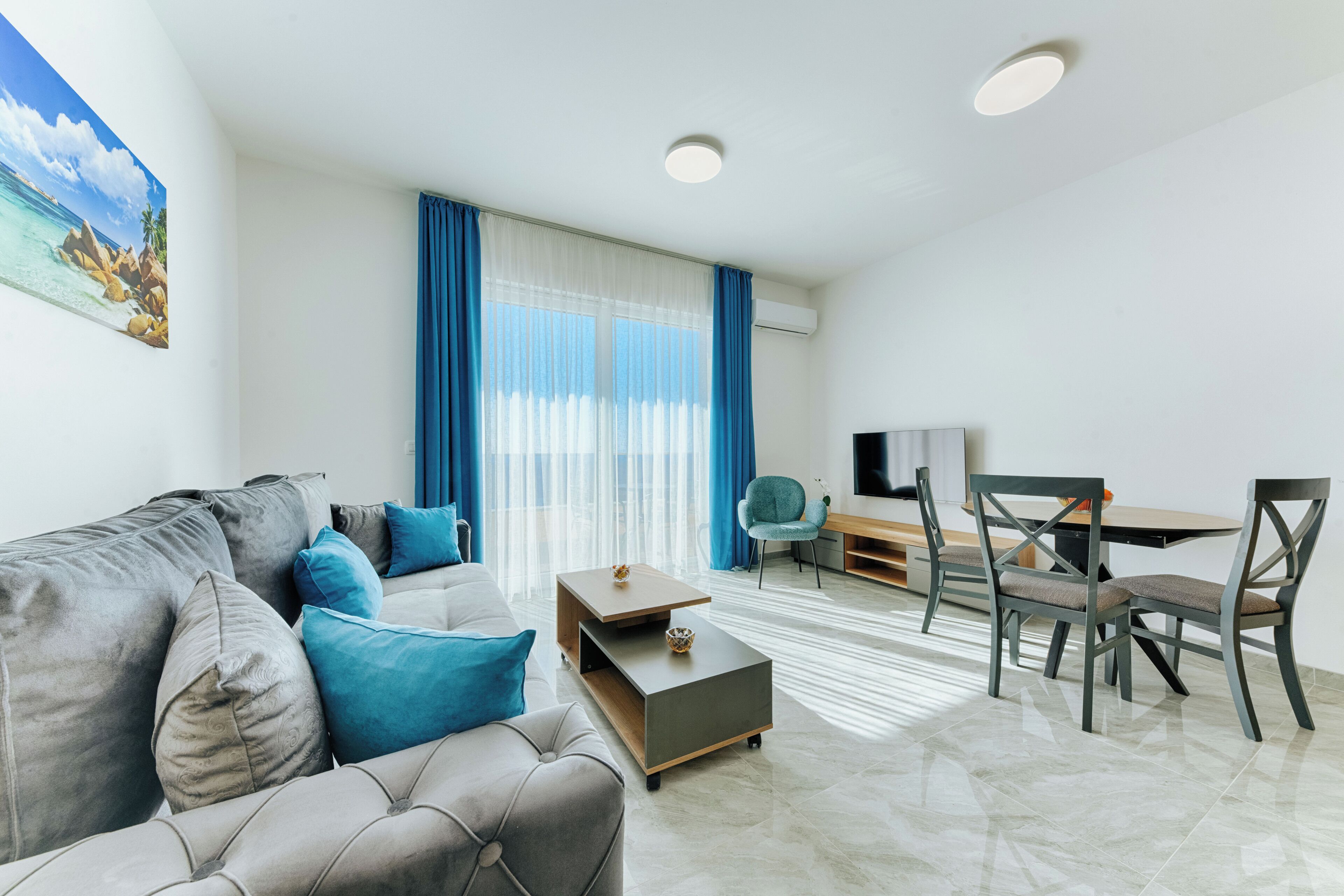 Una sala de estar moderna con un sofá, una mesa de centro y un comedor con sillas y un televisor.