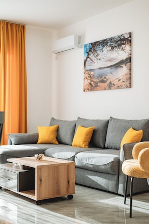 A modern living room with a grey sofa, yellow cushions, a wooden coffee table, and a painting on the wall. - ARA Lux Apartments (Utjeha)