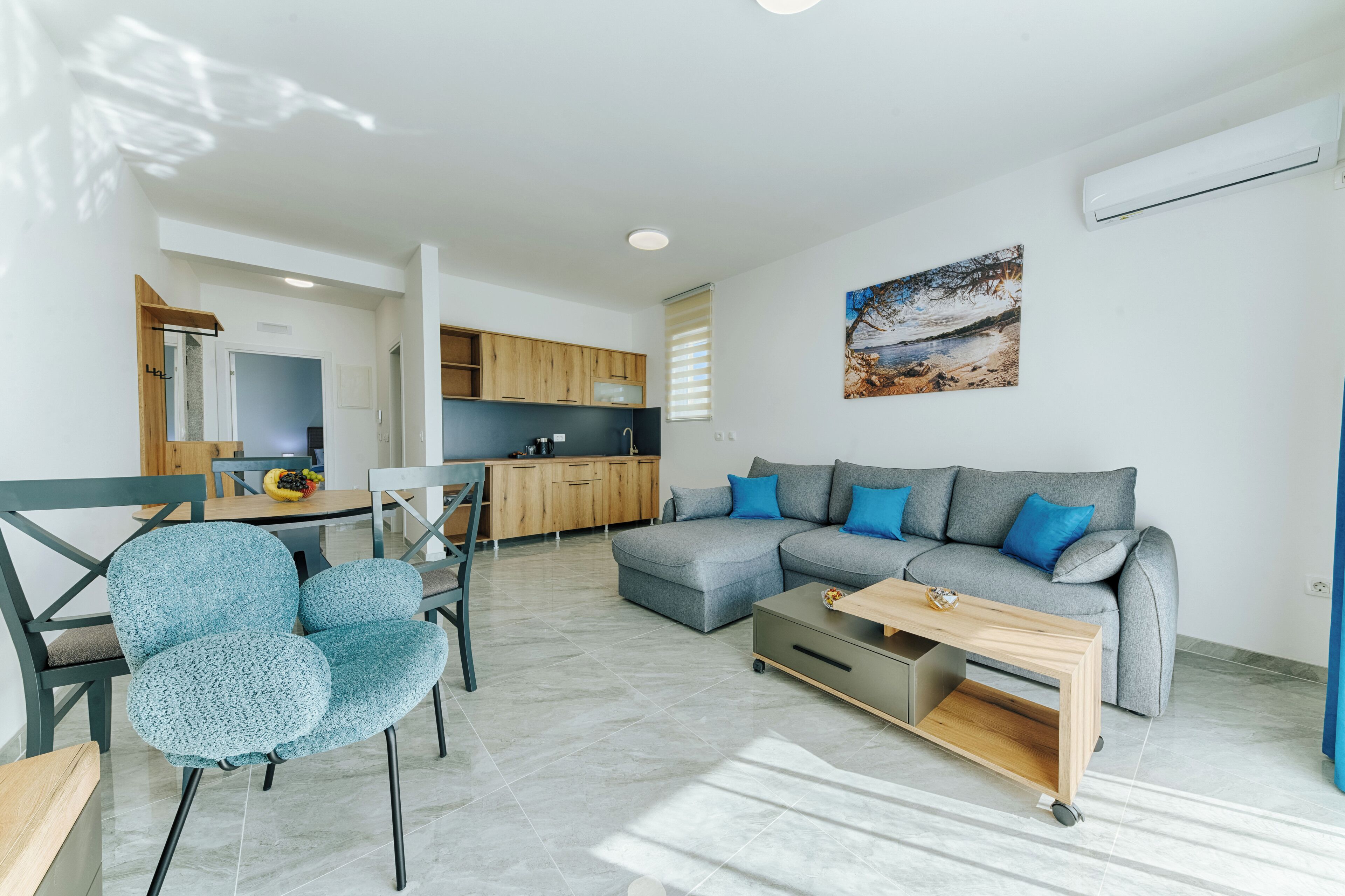 A modern living room with a grey sectional sofa, a blue armchair, and a wooden coffee table.