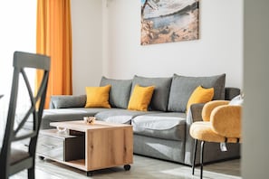 A modern living room with a grey sofa, yellow cushions, a wooden coffee table, and a painting on the wall. - ARA Lux Apartments (Utjeha)