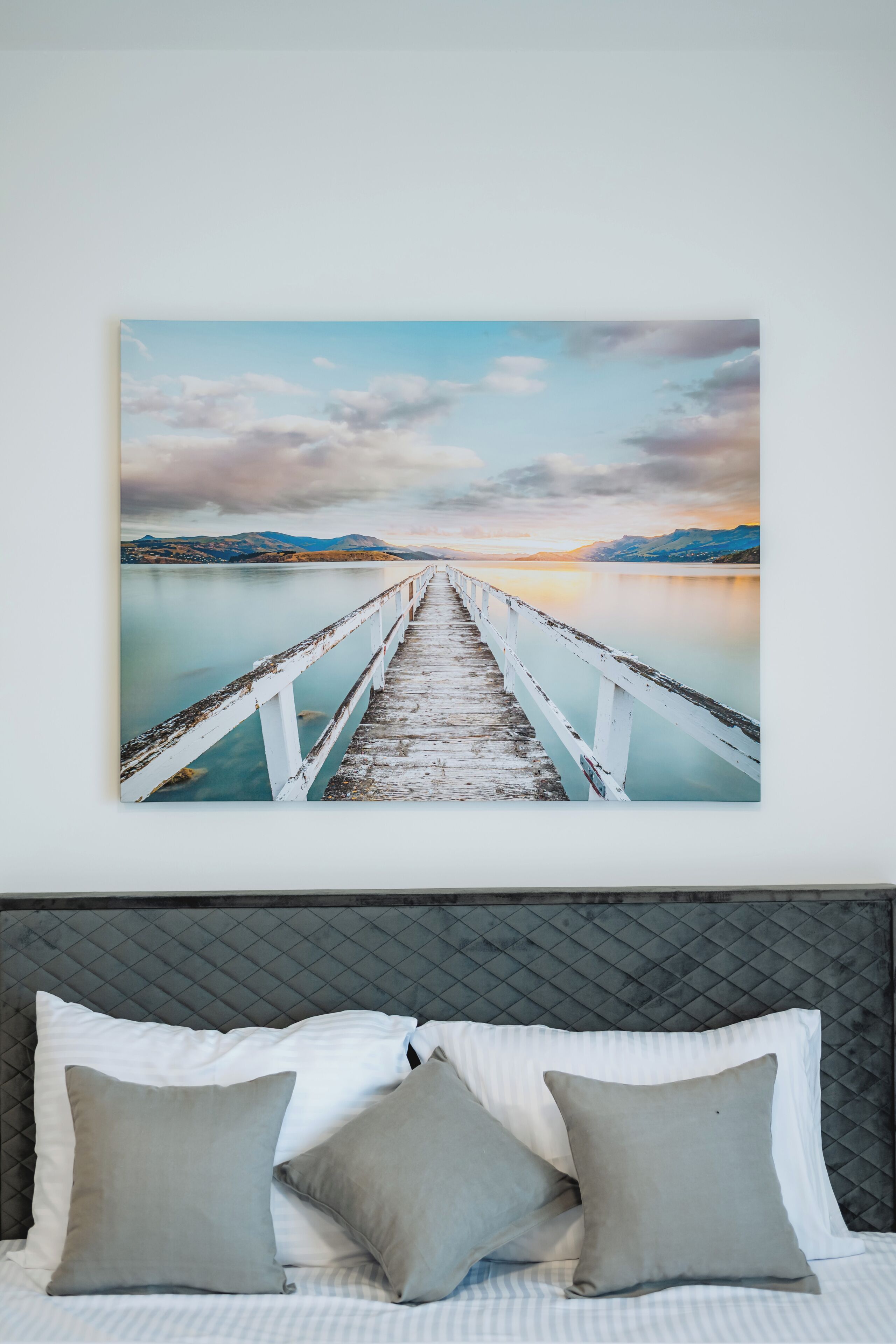 Un dormitorio con cama, almohadas y un cuadro colgado en la pared de un muelle.