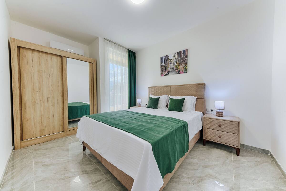 Une chambre à coucher avec un lit, une table de chevet, une commode et un tableau au mur.