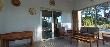 A room with a sliding glass door leading to an outdoor area, wooden furniture, and a wall-mounted hat.